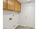 Bright laundry room featuring wood cabinets, wood-look flooring, and washer/dryer hookups at 7501 Bush Garden Ave, Las Vegas, NV 89129