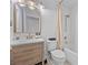 Bright bathroom with white tiling, wood vanity, decorative mirror, and shower-tub combo at 7542 Peaceful Brook St, Las Vegas, NV 89131