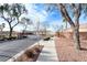 Community entrance with paved road, sidewalk, desert landscaping, and brick privacy wall at 8519 Little Fox St, Las Vegas, NV 89123