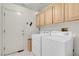 Practical laundry room includes a washer, dryer, and upper cabinets for storage at 1433 Erskine Ave, Las Vegas, NV 89123