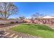 A gravel backyard with a patch of artificial grass, desert landscaping, and a perimeter block wall at 258 Spring River Ave, Las Vegas, NV 89123