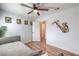 Sun-filled bedroom with wood-look floors, ceiling fan, gray daybed and saxophone wall art at 500 Duchess Ave, North Las Vegas, NV 89030