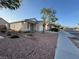 A charming single story home features desert landscaping with a sidewalk on a clear day at 6165 Highland Gardens Dr, North Las Vegas, NV 89031