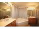 Bright bathroom with double vanity, mirrors, and a separate tub with shower curtain at 6437 Boatbill St, North Las Vegas, NV 89084