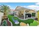 A backyard featuring artificial turf, a covered patio, desert landscaping and various seating areas at 688 Quiet Stream Ct, Henderson, NV 89052