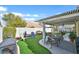 Backyard with artificial turf, covered patio, seating, desert landscaping and white block wall at 688 Quiet Stream Ct, Henderson, NV 89052