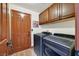 Laundry room with side-by-side washer and dryer, wood cabinets and a door to the backyard at 688 Quiet Stream Ct, Henderson, NV 89052