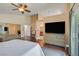 Bright main bedroom with an adjacent bathroom, television, ceiling fan, and hardwood floors at 688 Quiet Stream Ct, Henderson, NV 89052