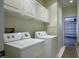 Bright laundry room featuring a washer, dryer, white cabinets, and access to the garage at 726 Sea Pines Ln, Las Vegas, NV 89107