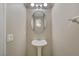 Chic half-bathroom with a pedestal sink, neutral walls, and an oval mirror, offering a clean and simple space at 7530 Brisa Del Mar Ave, Las Vegas, NV 89179