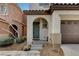 The front entrance to the house features a arched doorway and a two car garage at 7530 Brisa Del Mar Ave, Las Vegas, NV 89179