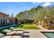 This backyard features artificial turf, paver patios, mature trees, and a luxury main house at 9940 Orient Express Ct, Las Vegas, NV 89145
