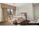 Upstairs guest bedroom featuring a cozy bed, an upholstered chair, and a balcony overlooking the greenery at 9940 Orient Express Ct, Las Vegas, NV 89145