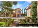 Detached casita with a three-car garage, lush landscaping, and a paved driveway, offering privacy and charm at 9940 Orient Express Ct, Las Vegas, NV 89145
