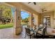 Covered patio with a glass-topped dining table and chairs overlooking the manicured garden at 9940 Orient Express Ct, Las Vegas, NV 89145