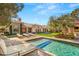 A backyard pool is surrounded by lounge furniture, an immaculate lawn, and an elegant home at 9940 Orient Express Ct, Las Vegas, NV 89145