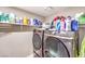 Modern laundry room with front-loading washer and dryer and white shelves full of supplies at 4125 Glenfield Cir, Las Vegas, NV 89129