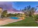 Lush backyard featuring a sparkling pool and spa, with mature landscaping and a picturesque sunset at 71 Fountainhead Cir, Henderson, NV 89052