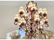 Close-up of a glamorous chandelier with ornate details, cascading crystals, and soft, ambient lighting at 9425 San Laguna Ct # 102, Las Vegas, NV 89134