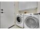 A bright laundry room with white washer and dryer and storage cabinets at 9425 San Laguna Ct # 102, Las Vegas, NV 89134