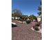 Landscaped backyard featuring decorative rock, mature trees, and colorful flowering plants at 9704 Brawley Dr, Las Vegas, NV 89134