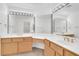 Bathroom with double sinks, wood cabinets, large mirrors with Hollywood lighting, and a vanity at 9704 Brawley Dr, Las Vegas, NV 89134