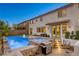 Beautiful backyard with pool, spa, outdoor kitchen, seating, and a two-story house with stucco exterior at 9950 Waxberry Ct, Las Vegas, NV 89178