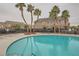 Inviting community pool surrounded by lounge chairs and palm trees, perfect for relaxing and enjoying the outdoors at 10147 Aspen Rose St # 101, Las Vegas, NV 89183