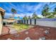 Expansive backyard featuring a covered patio, palm trees, and decorative landscaping at 1107 Cloudy Day Dr, Henderson, NV 89074
