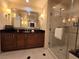 A vanity with rich wood cabinets, granite countertops, and decorative lamps is adjacent to a glass shower at 135 E Harmon Ave # 2120, Las Vegas, NV 89109