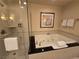 Bright bathroom featuring a glass shower and a luxurious jacuzzi tub with decorative wall art at 135 E Harmon Ave # 2120, Las Vegas, NV 89109