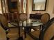 Close up of a round glass dining table with four chairs, set against a backdrop of elegant built-in cabinetry at 135 E Harmon Ave # 2120, Las Vegas, NV 89109