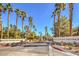 Community entrance featuring lush palm trees and 'Isla at South Shores' signage on a sunny day at 2101 Sealion Dr # 105, Las Vegas, NV 89128