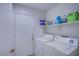 Functional laundry room with washer, dryer, and storage shelves at 320 Ellen Marie Dr, Las Vegas, NV 89110