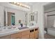 Bathroom featuring double sinks, wood cabinets, large mirror and a door leading to the toilet and shower at 399 Placer Creek Ln, Henderson, NV 89014