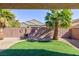 Private backyard with artificial turf, desert landscaping, palms, and decorative accents at 4012 Shetland Pony St, Las Vegas, NV 89122