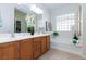 Bright bathroom featuring a double sink vanity, tiled floors, and a soaking tub with a glass block window at 4012 Shetland Pony St, Las Vegas, NV 89122
