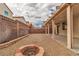 Backyard featuring a brick fire pit, gravel ground cover, and a covered patio with string lights at 6949 Copper Bracelet Ave, Las Vegas, NV 89122