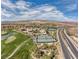Aerial view showcasing the community amenities with tennis courts, manicured grounds and nearby highway at 9 Promenade Isle Ln, Henderson, NV 89011