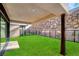 Covered patio with a stone wall and green grass at 9 Promenade Isle Ln, Henderson, NV 89011