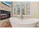 Bright bathroom with a modern soaking tub, fireplace, and plantation shutters at 9044 Opus Dr, Las Vegas, NV 89117