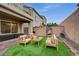 Inviting backyard with artificial grass, brick pavers, modern seating, and cozy hanging chair for outdoor enjoyment at 9835 Fox Estate St, Las Vegas, NV 89141