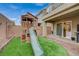 Backyard features a playhouse with a slide, artificial turf, and access to the home through a sliding glass door at 9835 Fox Estate St, Las Vegas, NV 89141