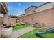 Backyard oasis with artificial turf, a brick paver patio, and a cozy seating area perfect for relaxation at 9835 Fox Estate St, Las Vegas, NV 89141