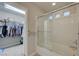 Well-lit bathroom featuring tub with glass door, showerhead and walk-in closet at 9835 Fox Estate St, Las Vegas, NV 89141