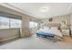 Well-lit primary bedroom with a tray ceiling, plush carpeting, and a cozy blue bench at 9835 Fox Estate St, Las Vegas, NV 89141