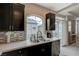 Contemporary kitchen featuring a double sink, stainless steel dishwasher, dark cabinets and access to the outdoor patio at 9835 Fox Estate St, Las Vegas, NV 89141