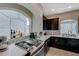 Modern kitchen with stainless steel appliances, quartz countertops, dark cabinets, and a view through an arched window at 9835 Fox Estate St, Las Vegas, NV 89141