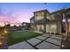 An exterior elevation of a home at dusk showcasing a putting green and outdoor kitchen at 13 Scenic Terrain Ave, Henderson, NV 89011