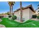 A landscaped backyard with vibrant artificial grass, mature palm trees, and a well-maintained exterior at 1700 Brock Ct, Las Vegas, NV 89117